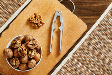 Walnuts and nutcracker on a cutting board and wooden table