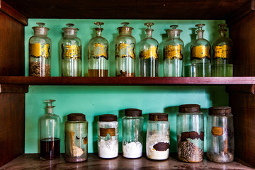 Antique Apothecary Jars in an Brown Cabinet Shelves Turquoise Blue Background
