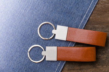 Leather key chain with blue fabric on wooden background