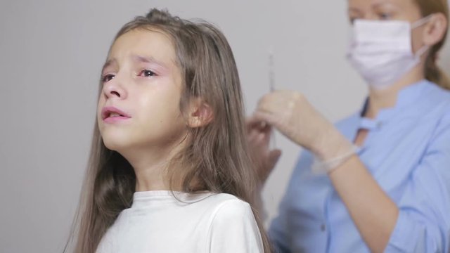 little girl is afraid of the doctor with a syringe. baby cries afraid injection