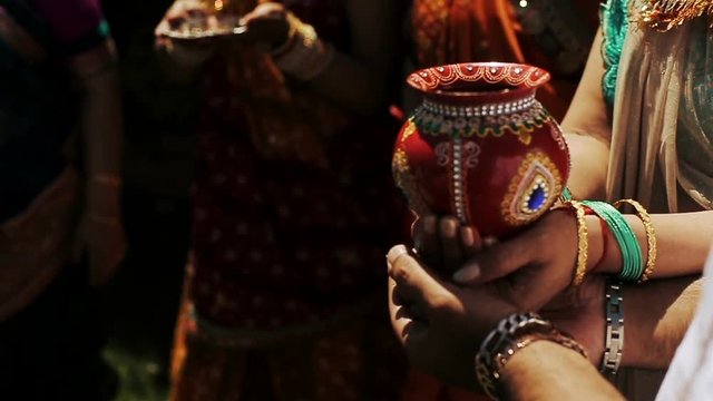 Indian bride and her parents hold red bowl with jewels in their hands