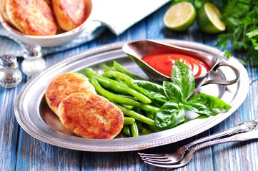 Delicious fish cakes with boiled green beans and tomato sauce