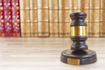 Obraz na płótnie Canvas Wooden Law Gavel on table against a row of law books