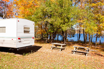 RV camped in fall forest on lakeshore campsite