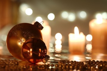 Golden Christmas balls and beads with reflection against candlelight background