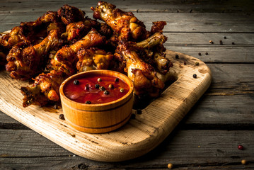 Chicken wings barbecue on a wooden table with tomato sauce and spices