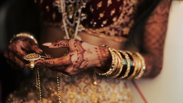 Red and golden bracelets put over the hands of Indian bride