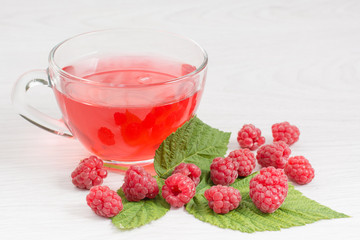 Ягоды и листья малины и чашка с компотом на столе