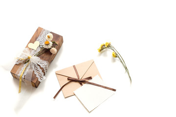 Beautiful handmade gift box (package) with flowers, envelope with blank gift tag and decorative rope on white background. Wooden gift box. Vintage Style. BOHO