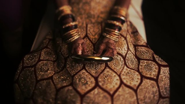 Hands with golden bracelets hold mirror on the knees
