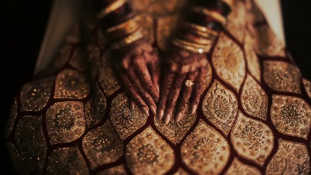 Closeup of Indian bride's hands covered with mehndi and holding a golden necklace
