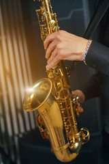 Obraz premium Musical instrument saxophone close-up. Hands on a musical instrument. Young guy playing jazz.