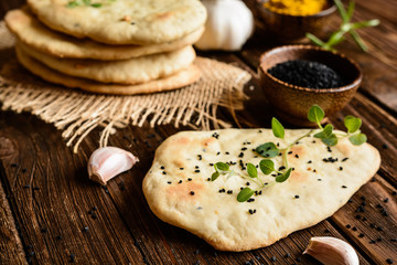 Traditional Indian Naan bread with garlic on a wooden background