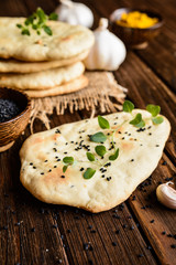 Traditional Indian Naan bread with garlic on a wooden background © noirchocolate