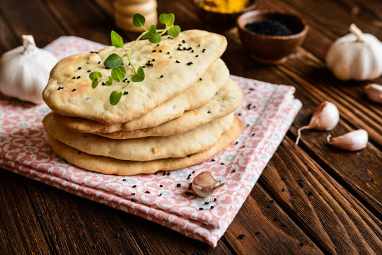 Traditional Indian Naan bread with garlic on a wooden background