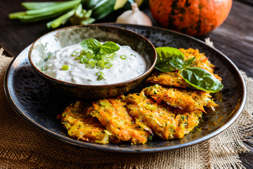 Pumpkin pancakes with zucchini and served with sour cream dip