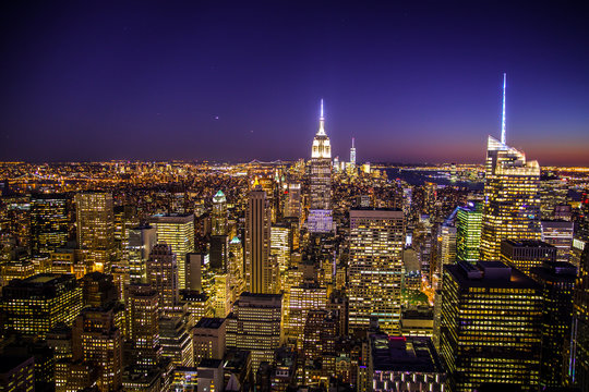 Fototapeta View of across lit buildings of New York City from midtown Manhattan at night  