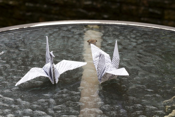 Bird folded white paper on the table in the garden.