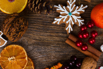 frame with christmas gingerbread snowflake cookie, spices and decorations close up on wood