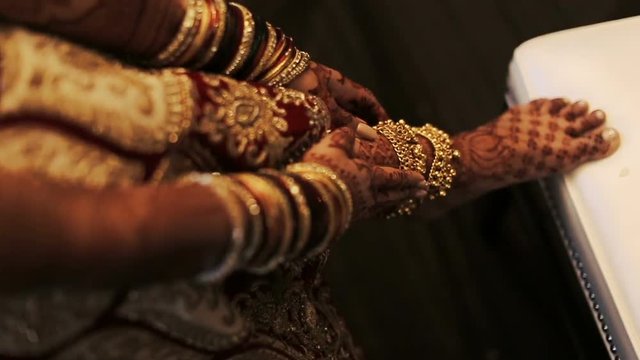 Mehndi covers delicate Indian bride's hands full of bracelets