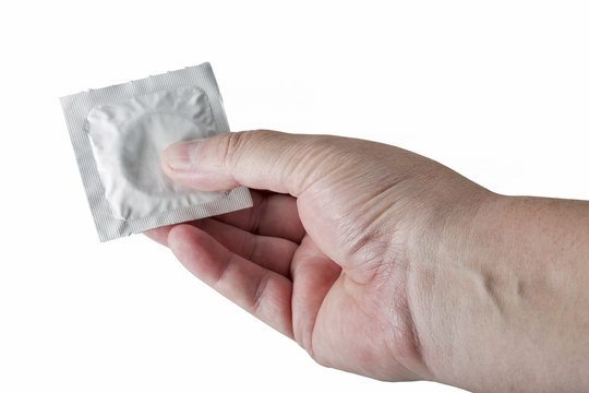 Hand holding a condom isolated on white background