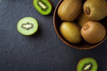 Fresh kiwi in a wooden bowl on a black