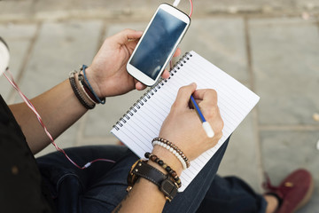 Man hands using smartphone and writing on notebook