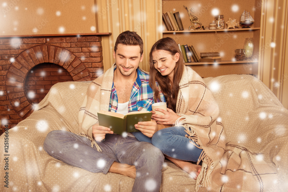 Poster beautiful couple in love reading book on the snowy background