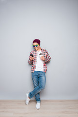 Fototapeta premium Young man in cap and glasses holding cup of coffee and typing sm