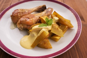 Roasted chicken drumsticks served on the old vintage porcelain plate with baked sweet potatoes and...