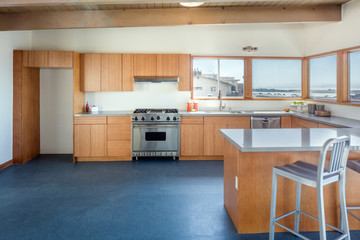 Wooden kitchen in modern home with sea view and stainless steel appliances. 