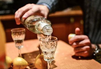 Man pouring strong alcoholic drink vodka in glass