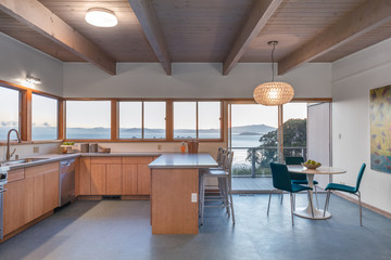 Wooden kitchen in modern home with sea view and seating arrangement.