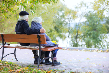 Senior couple sitting on bench in autumn park 