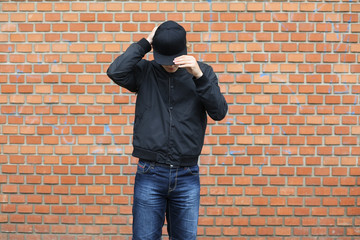 Portrait of attractive teenage boy standing  in front of a brick wall.