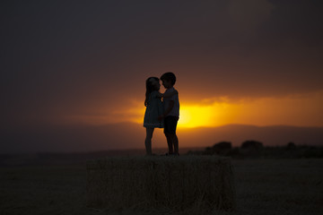 pareja de ni&ntilde;os sobre el trigo disfrutando de la puesta de sol