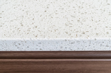 Closeup shot of white granite countertop over brown wooden kitch