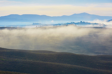 Obraz premium Scenic view of Tuscan fields and hills with fog