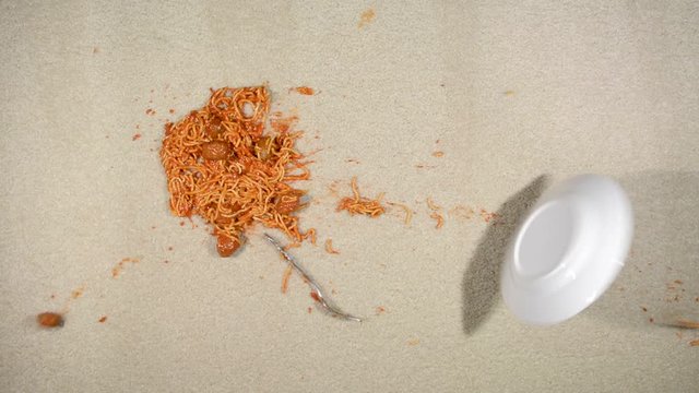 Slow motion video of a spilling plate of spaghetti on clean, white carpet .