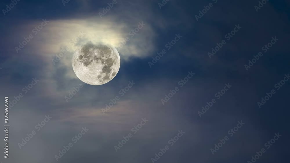 Wall mural fog moves across a full moon framed against a moody, blue sky with cloud cover..