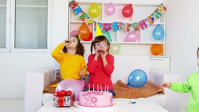 A group of children at a birthday party, blowing out party horn.Slow motion, high speed camera