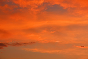 Evening sky at sunset in scarlet colors with orange dense clouds