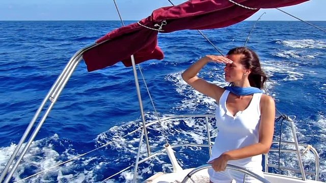 Beautiful lady skipper navigating a sailboat.Slow motion, high speed camera