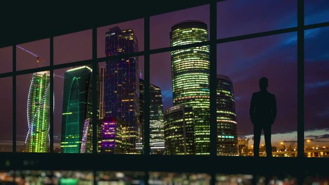 5 in 1 video! The man stand at the panoramic window on the background of skyscraper. Time lapse. Wide angle
