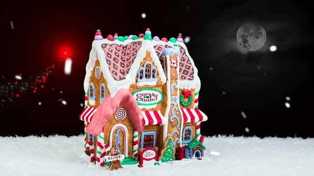 A rotating gingerbread house during a snowy Christmas holiday.