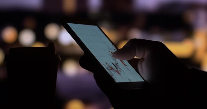Using smart phone with stock market graph and chart