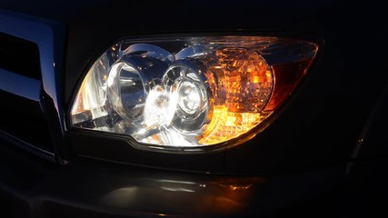 A car blinker and headlight at night used for safety and signaling for turns.