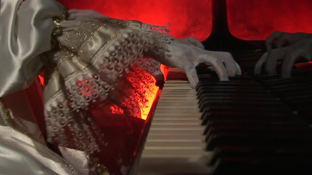 An elderly man playing an old, antique piano with strong, dramatic lighting and smoke.