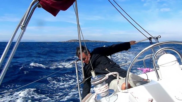 Mature adult skipper driving a sailboat. Slow motion and High speed camera.