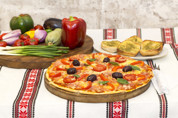 Tasty pizza with vegetables, basil, olives, tomatoes, green pepper.